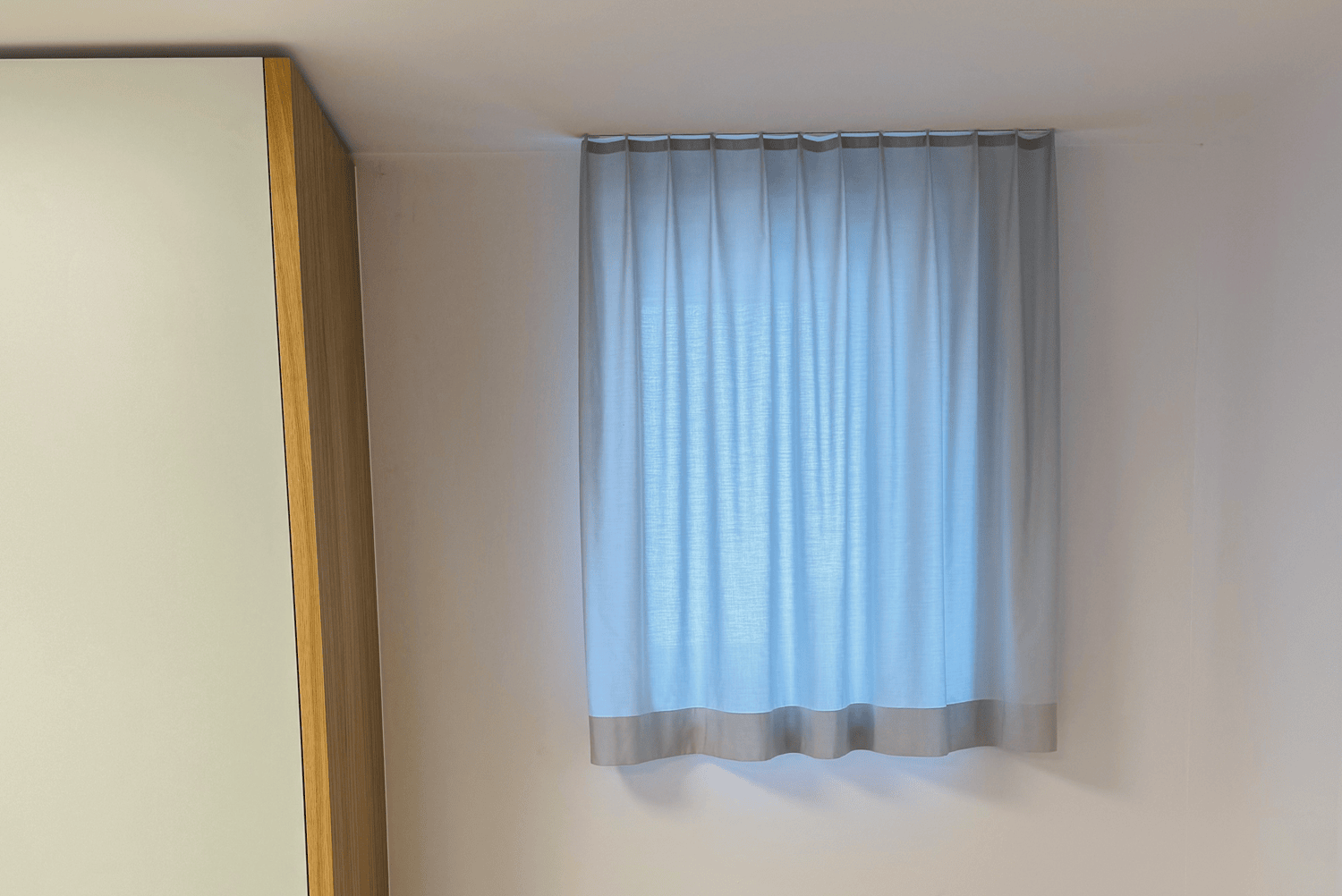 Vor einem kleinen Fenster h&auml;ngt ein Vorhang, der dennoch das Tageslicht rein l&auml;sst